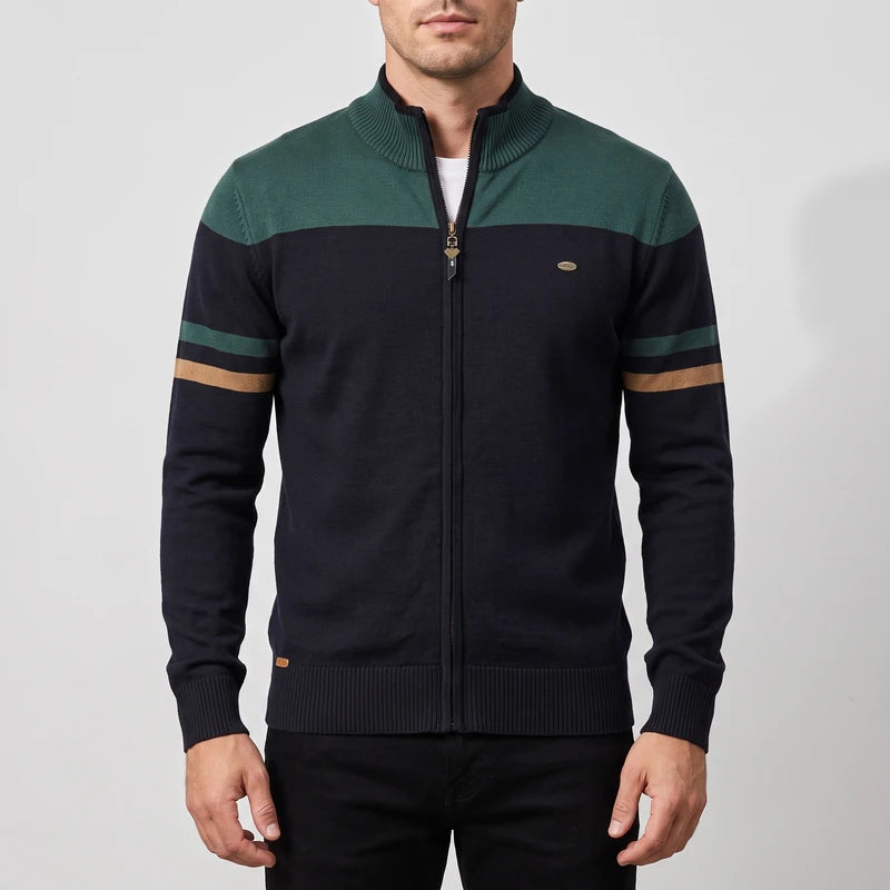 Man wearing a dark blue zip-up sweater with a dark green top block and two green and tan stripes on the left sleeve.